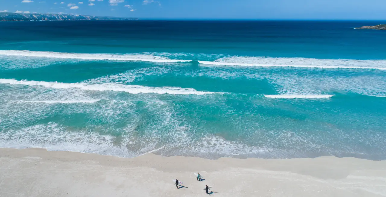Luftaufnahme von Surfern, die am Strand von Westaustralien entlanglaufen, mit dem klaren blauen Wasser des Indischen Ozeans [Bildquelle: © Tourism Western Australia]