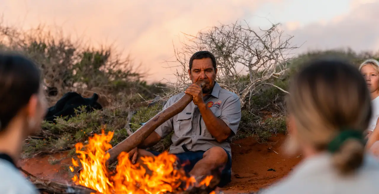 Ein Aboriginal-Guide spielt Didgeridoo am Lagerfeuer während einer Wula Gura Nyinda Eco Cultural Adventure in Westaustralien [Bildquelle: © Tourism Western Australia]