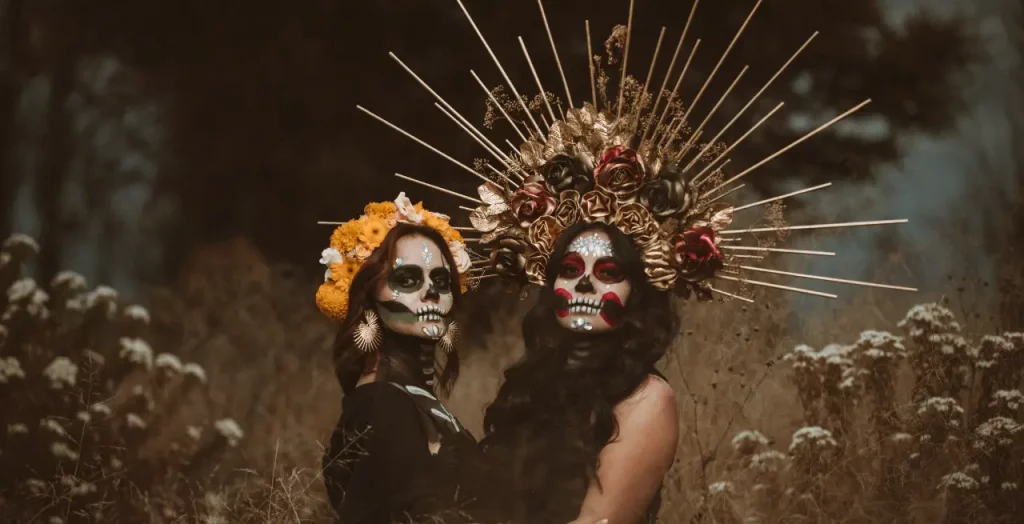 Zwei Frauen am Día de los Muertos mit kunstvollem Totenkopf-Make-up und prächtigen Blumenkronen. [Bildquelle: © Fernando Capetillo | Canva]