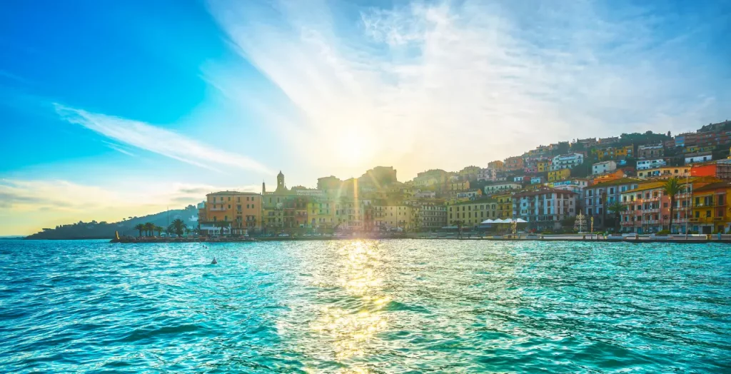 Sonnendurchflutetes Panorama auf Porto Santo Stefano, Toskana, Italien, mit Blick auf die bunten Fassaden und das glitzernde Meer [Bildquelle: © StevanZZ | Canva]